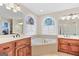 Bathroom with double sinks, tub, wood cabinets, and stained glass windows at 643 Old Greenville Rd, Fayetteville, GA 30215