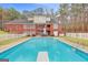 Backyard pool with diving board and patio area, framed by a red brick home and lush lawn at 643 Old Greenville Rd, Fayetteville, GA 30215