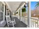 Inviting front porch with white rocking chairs, columns, hanging ferns and a decorative clock at 300 Tarragon Dr, Fayetteville, GA 30215