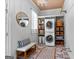 Bright laundry room with stacked washer/dryer, ample storage shelves with baskets, and unique patterned tile flooring at 300 Tarragon Dr, Fayetteville, GA 30215
