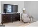 Bedroom seating area featuring an armchair, end table, dresser with TV, and a lamp at 300 Tarragon Dr, Fayetteville, GA 30215