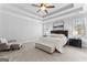 Spacious bedroom featuring a tray ceiling, ceiling fan, seating area, and a large bed with bench at 300 Tarragon Dr, Fayetteville, GA 30215