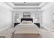 Large bedroom with tray ceiling, bed with bench, and art between two windows at 300 Tarragon Dr, Fayetteville, GA 30215