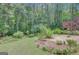 Picturesque backyard with a stone patio, lush landscaping, and tree-lined border at 140 Rockglen Ct, Fayetteville, GA 30215