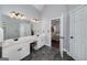 Bright bathroom featuring double sinks, gray tile floors, and an open doorway to the main bedroom at 149 Crown Glen Way, Stockbridge, GA 30281