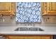 Close-up of stainless sink and modern faucet under window, framed with wood cabinets and patterned tile backsplash at 2808 Autumn Lake Ln # D/6, Decatur, GA 30034