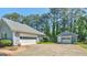 A two car garage with a detached garage and a paved driveway surrounded by lush greenery and trees at 230 Acorn Ct, Mcdonough, GA 30253