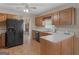 An eat-in kitchen featuring wooden cabinets, a black refrigerator, and a view of a brick fireplace at 230 Acorn Ct, Mcdonough, GA 30253