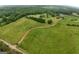 Expansive aerial view of green pastures, a winding driveway, and a charming farmhouse nestled among mature trees at 1761 Reavesville Rd, Bowdon, GA 30108
