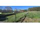 Exterior shot of the red barn, fence and the expansive grass lands that surround the property at 1761 Reavesville Rd, Bowdon, GA 30108