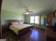 Spacious bedroom featuring hardwood floors, a ceiling fan, a window, and a large wood bed frame with yellow striped bedding at 1761 Reavesville Rd, Bowdon, GA 30108