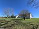 Exterior view of a home on a grassy lot under a blue sky with a few trees at 1761 Reavesville Rd, Bowdon, GA 30108