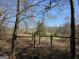 Scenic property view through a rustic fence, featuring mature trees and lush greenery at 1761 Reavesville Rd, Bowdon, GA 30108