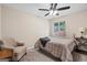 Cozy bedroom with a ceiling fan, a comfy armchair, and a window providing natural light and views of the backyard at 1190 Plantation Dr, Villa Rica, GA 30180