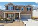 Two-story home featuring stone accents, a two-car garage, manicured landscaping, and a welcoming covered front porch at 6910 Newcastle Ct, Fairburn, GA 30213