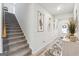 Well-lit hallway with carpeted stairs, stylish wall art, and a view of the front door and a console table at 6910 Newcastle Ct, Fairburn, GA 30213