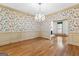 Elegant dining room with a crystal chandelier, floral wallpaper, and hardwood floors at 180 Habersham Pl, Fayetteville, GA 30214