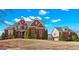 Elegant brick home on a landscaped lawn with blue sky and cloud background at 560 Birkdale Dr, Fayetteville, GA 30215