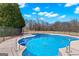 Sparkling in-ground pool with concrete surround and black metal safety fence at 560 Birkdale Dr, Fayetteville, GA 30215
