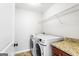 Well-lit laundry room featuring a modern washer and dryer set, granite countertop, and shelving at 1045 Kirkland Cir, Smyrna, GA 30080