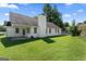 Back of a white-sided home with a chimney, large windows, and a sprawling green lawn at 217 Crystal Ct, Hampton, GA 30228