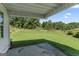 Backyard featuring a covered concrete patio that overlooks lush green grass and a wooded view at 217 Crystal Ct, Hampton, GA 30228