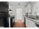 Galley kitchen features white cabinets, granite countertops, black appliances and hardwood flooring at 217 Crystal Ct, Hampton, GA 30228