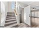 Well-lit staircase with carpet and hardwood flooring, adjacent to a bright living room and entry door at 821 Hood Rd, Fayetteville, GA 30214