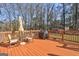 A wooden deck is ready for entertaining with a table, chairs, and grill overlooking a wooded backyard at 110 Paces Dr, Fayetteville, GA 30215