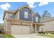 Charming home features a two-car garage, brick accents, and a well-manicured lawn at 312 Maddi Grace Ct, Locust Grove, GA 30248