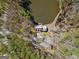 Aerial shot of a house with a brown roof next to a pond surrounded by woods and a long driveway at 897 Winding Trl, Lawrenceville, GA 30046