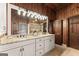 Wood-paneled bathroom featuring granite counters, dual sinks, and ample vanity lighting at 897 Winding Trl, Lawrenceville, GA 30046