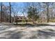 Inviting two-story home with a covered front porch, surrounded by trees and a gravel driveway at 897 Winding Trl, Lawrenceville, GA 30046