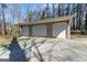 Spacious three-car garage with white doors and ample parking space on a gravel driveway at 897 Winding Trl, Lawrenceville, GA 30046