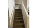 Carpeted staircase with white banister leading upstairs, showcasing a simple and functional design at 2478 Oakleaf Rdg, Lithonia, GA 30058