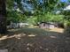 Backyard featuring a large grassy area and a shed, surrounded by mature trees at 360 Meadowbrook Dr, Mcdonough, GA 30253