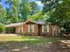 Quaint brick home with a metal roof, carport, and a spacious front yard surrounded by mature trees at 360 Meadowbrook Dr, Mcdonough, GA 30253