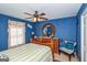 Bedroom with blue walls and featuring a fan, dresser, and decorative round mirror at 3435 Pierce Arrow Cir, Suwanee, GA 30024