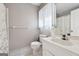 Well-lit bathroom with a sink vanity, soft wallpaper, and a shower-tub combination, creating a soothing space at 2200 Gleneagle Nw Ct, Conyers, GA 30012