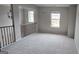 Open loft area with neutral walls, carpet, decorative railing, and natural light from two windows at 336 Traditions Ln # 147, Hampton, GA 30228