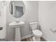 Bathroom with pedestal sink, round mirror, and elongated toilet at 3725 Heron Creek Ct, Loganville, GA 30052