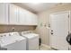 Laundry room with washer, dryer, cabinets, tile floors, and a door to the outside at 305 Cranmore Pl, Villa Rica, GA 30180