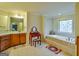 Bright bathroom features a soaking tub with tile surround, vanity and a decorative vanity table at 5997 Wildcreek Rd, Sugar Hill, GA 30518