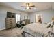 Spacious main bedroom featuring a ceiling fan, dresser, and black sofa seating area at 5997 Wildcreek Rd, Sugar Hill, GA 30518