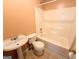 Full bath features peach walls, white tiled shower-tub and pedestal sink at 209 East Wilson St # 25, Villa Rica, GA 30180