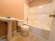 Full bath features peach walls, white tiled shower-tub and pedestal sink at 209 East Wilson St # 25, Villa Rica, GA 30180