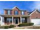 Beautiful brick home featuring a covered porch, black shutters, and green foundation shrubs at 7491 Hilltop Way, Atlanta, GA 30349