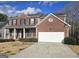 Traditional brick home with a two-car garage, inviting front porch, and well-kept lawn at 7491 Hilltop Way, Atlanta, GA 30349