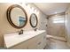 Bathroom with a dual sink vanity, decorative mirrors, marble floors, and a walk in shower at 1393 Vesta Ave, Atlanta, GA 30344