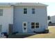 Back exterior featuring light blue siding, windows, and a small patio area with minimal landscaping at 7484 Knoll Hollow Rd, Lithonia, GA 30058